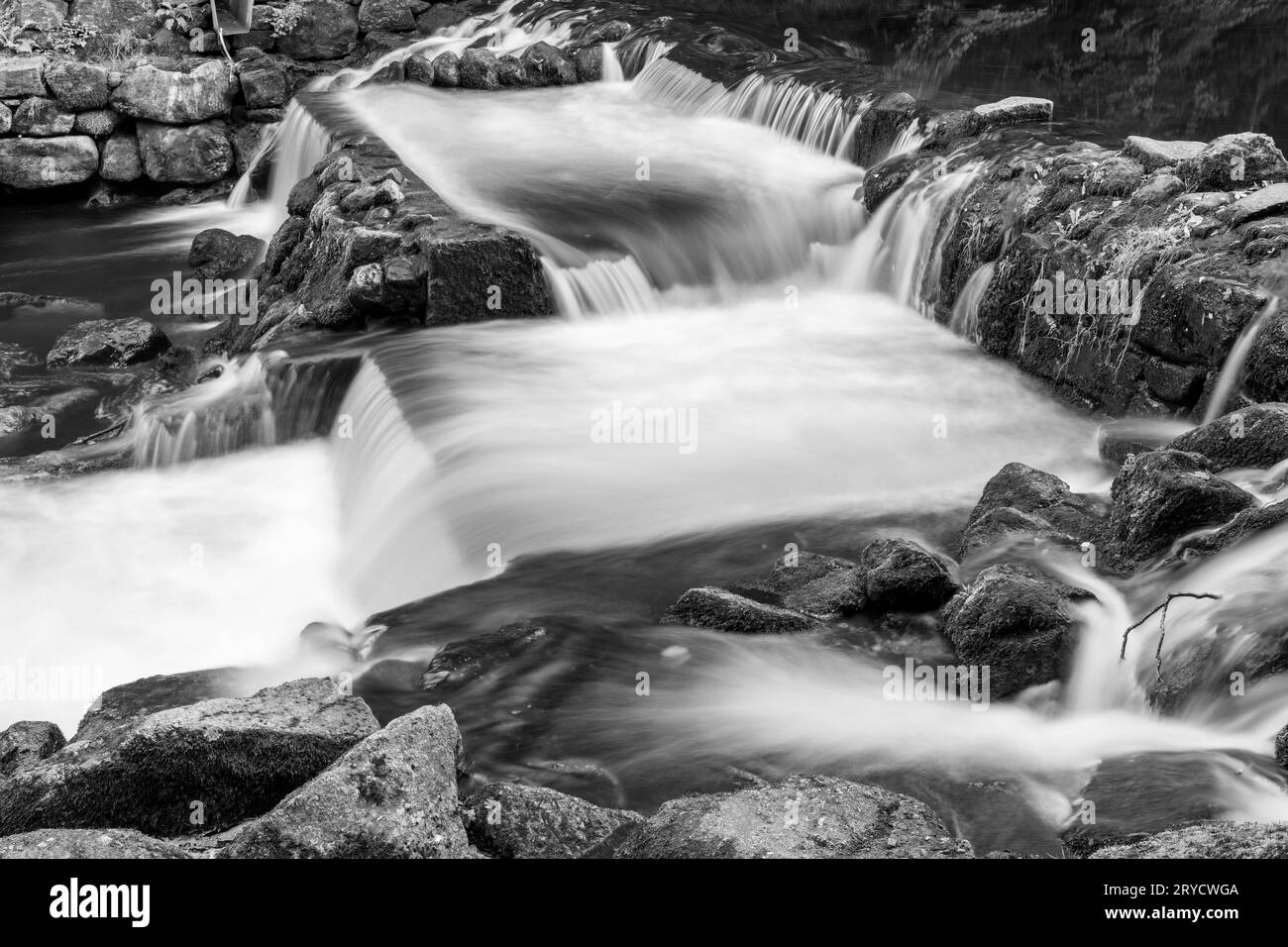 Longue exposition de la rivière Teign qui coule à travers le déversoir du château de Drogo dans le parc national de Dartmoor Banque D'Images