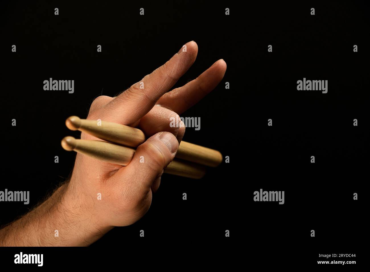 Main d'homme avec des baguettes de tambour et des cornes de diable sur noir Banque D'Images