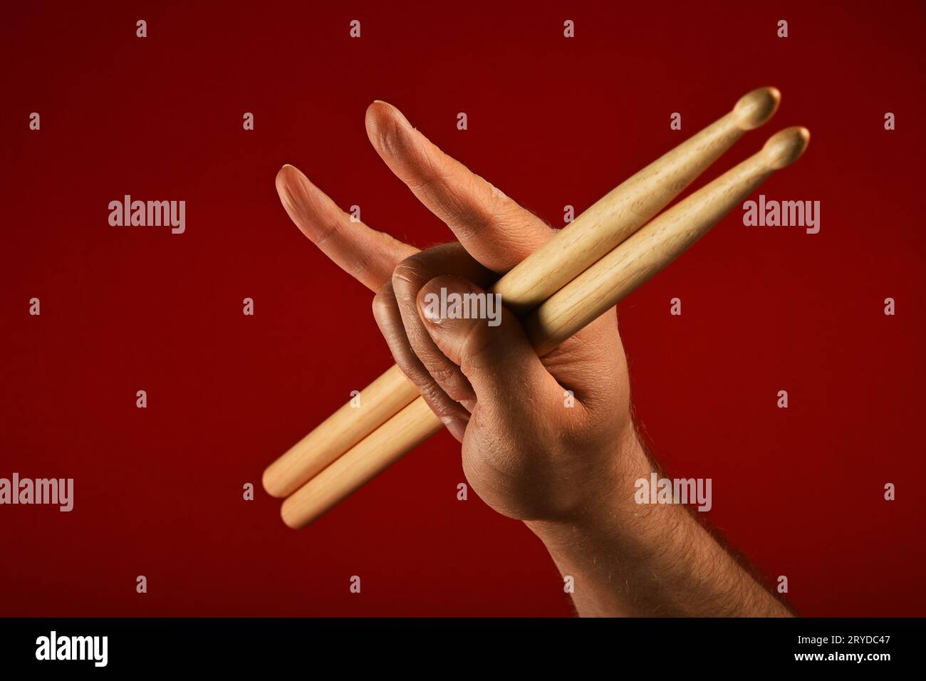 Main d'homme avec des baguettes de tambour et des cornes de diable sur rouge Banque D'Images