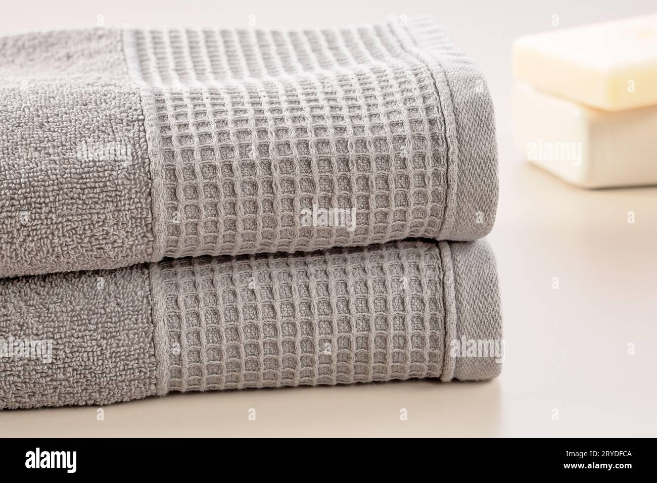 Accessoires de salle de bain. Pile de serviettes douces grises et barre de savon sur un fond gris. Banque D'Images