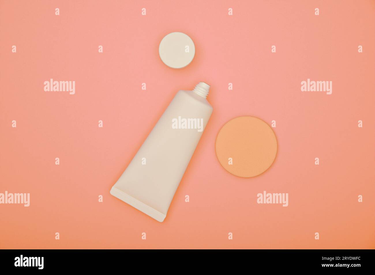 Tube blanc de crème de fond de teint et éponge sur rose Banque D'Images