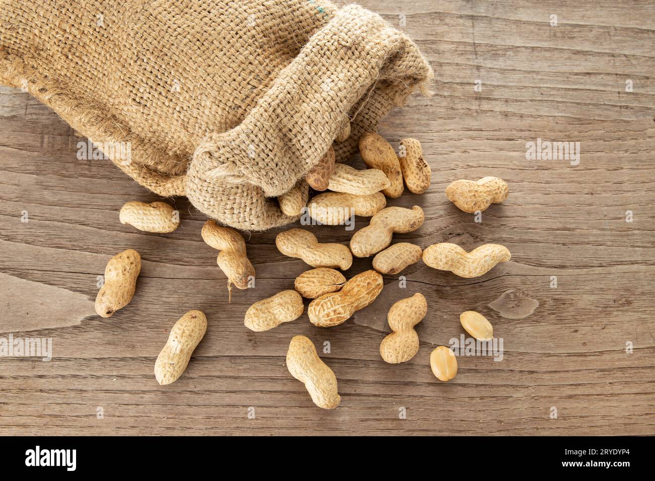 Sac en toile de jute et cacahuètes sur une table en bois rustique Banque D'Images