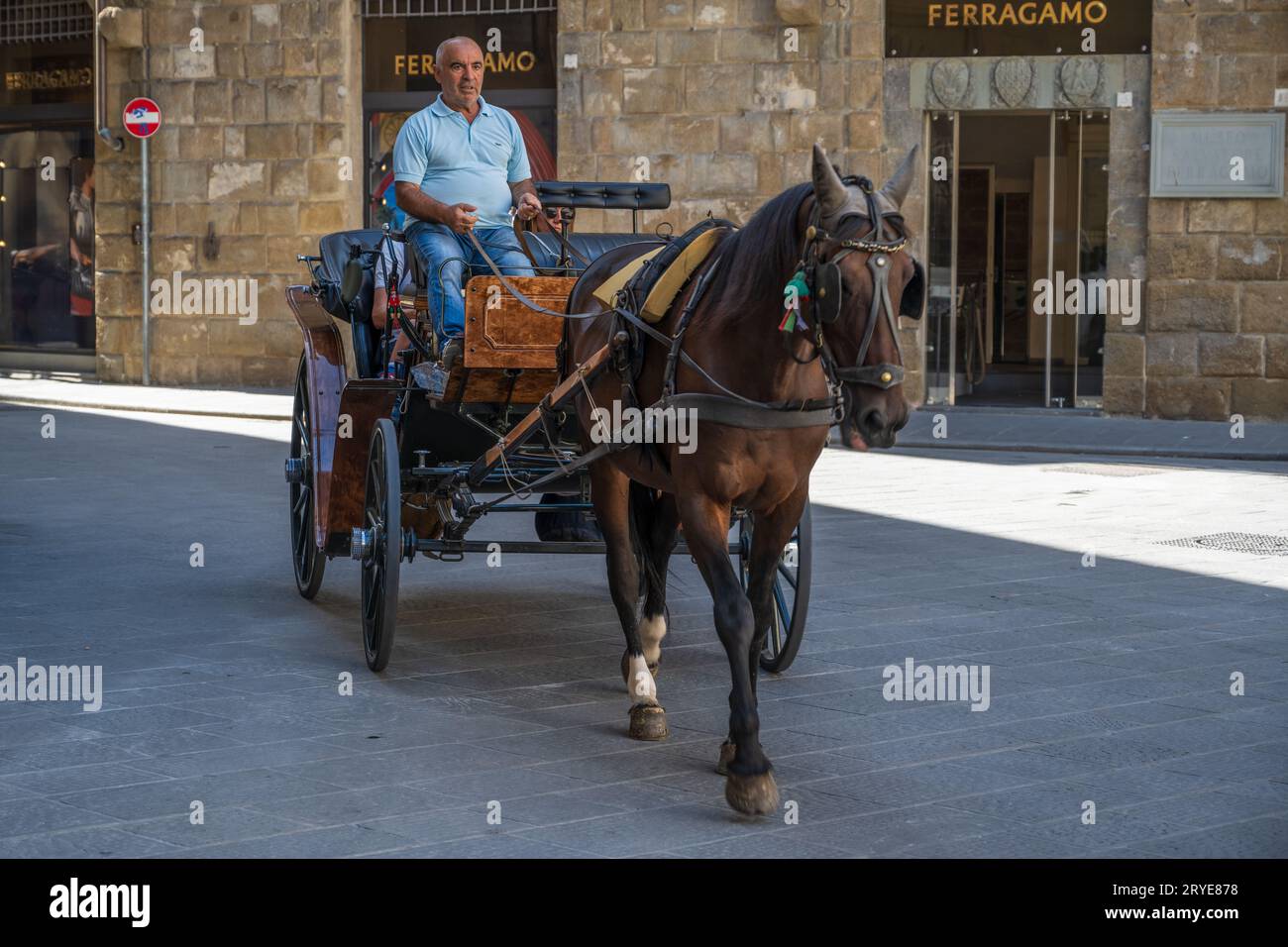 Florence, Italie--2 septembre 2023. Un chauffeur avec deux passagers à bord navigue à cheval et en calèche dans un quartier commercial chic de Floren Banque D'Images