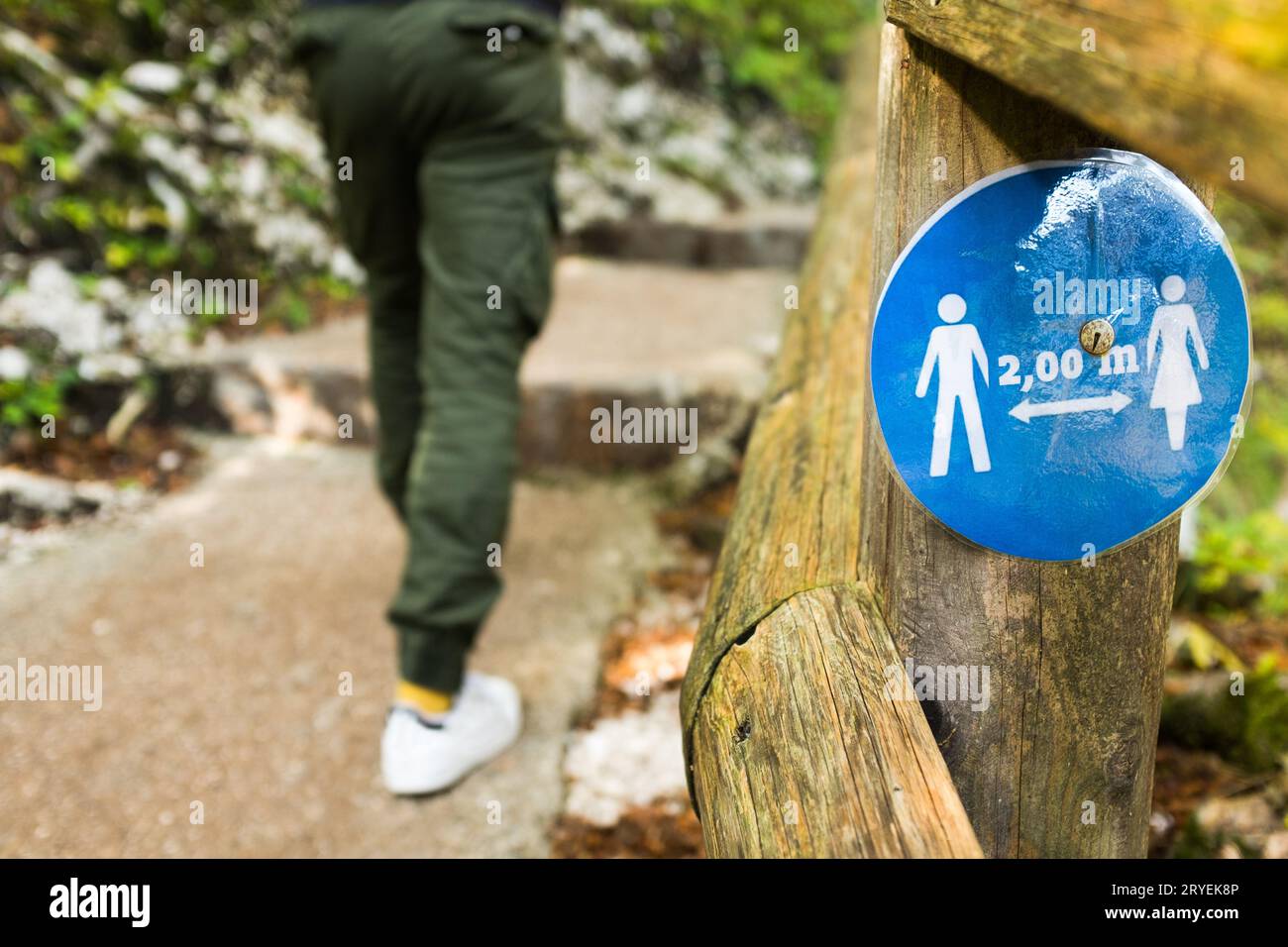 Panneau rond bleu sur une clôture en bois informant les gens de garder une distance sociale de 2 mètres Banque D'Images