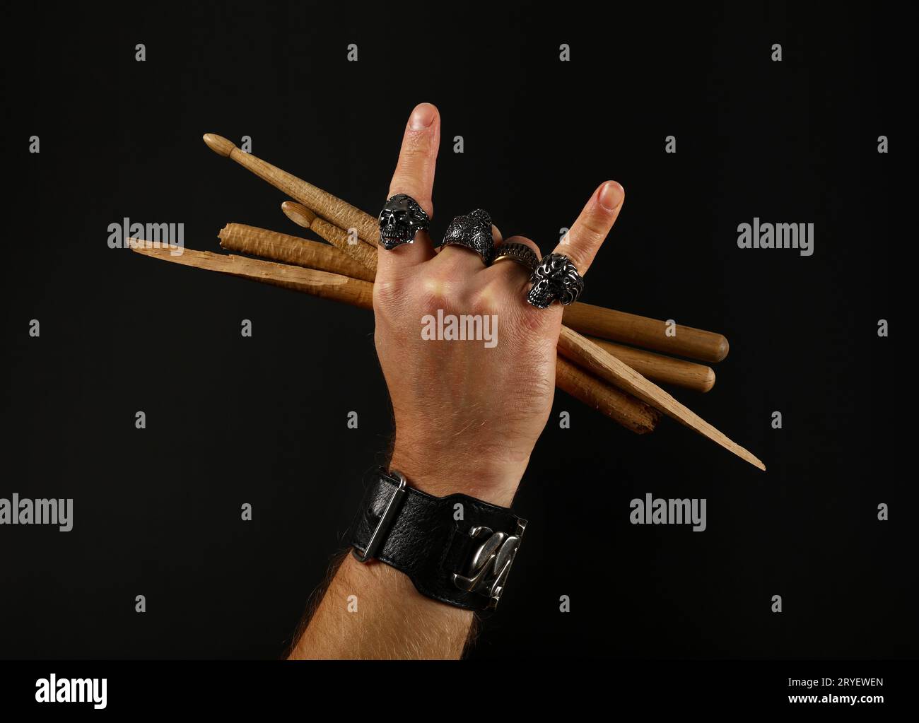 Main d'homme avec des baguettes de tambour et des cornes de diable sur noir Banque D'Images