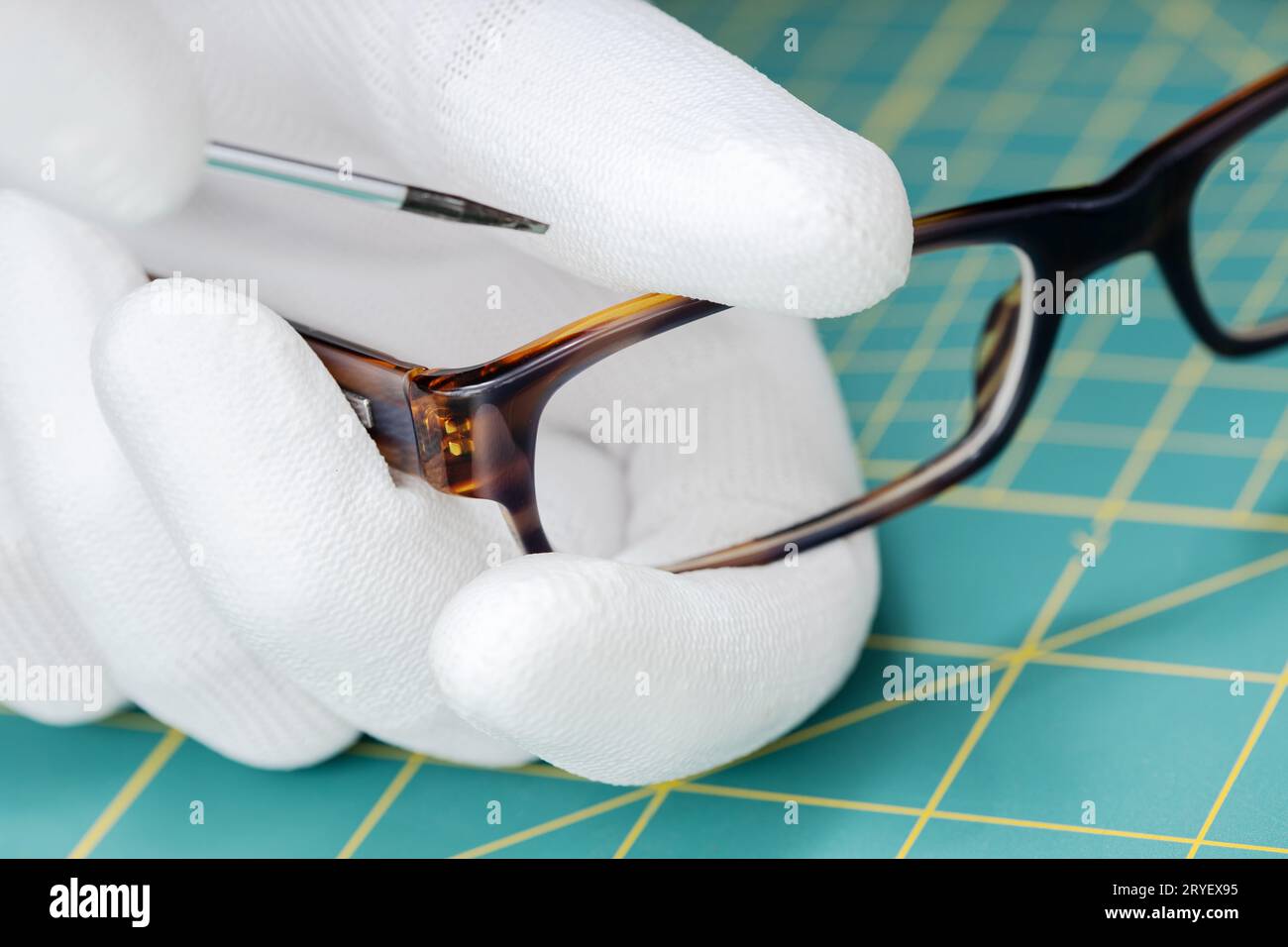 Les mains de l'opticien dans des gants réparant des lunettes avec un outil Banque D'Images Les mains de l'opticien dans des gants réparant des lunettes avec un outil Banque D'Images