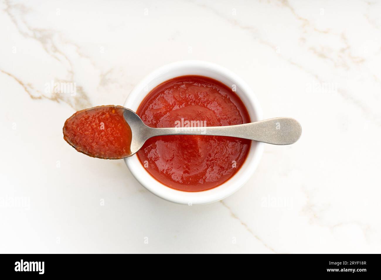 Sauce tomate fraîche sur un bol et cuillère sur une table en marbre blanc Banque D'Images Sauce tomate fraîche sur un bol et cuillère sur une table en marbre blanc Banque D'Images