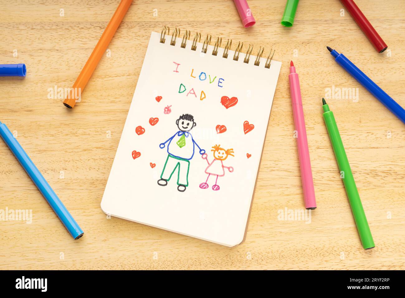 Concept de fête des pères. Carnet avec dessin d'un père avec une fille et marqueurs sur une table en bois Banque D'Images Concept de fête des pères. Carnet avec dessin d'un père avec une fille et marqueurs sur une table en bois Banque D'Images