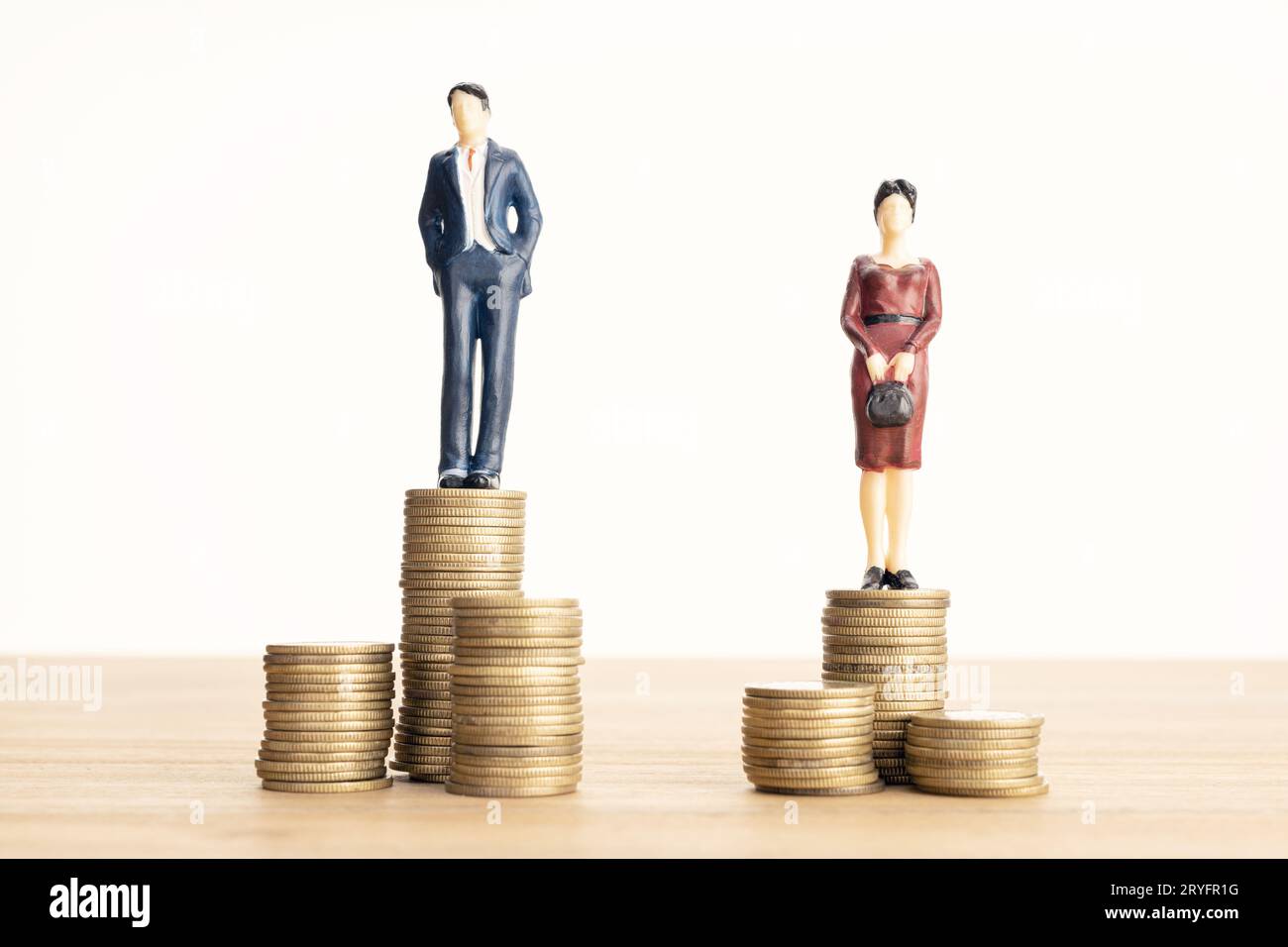 Notion : différence de salaire entre hommes et femmes. Homme et femme debout sur la pile de pièces de monnaie Banque D'Images