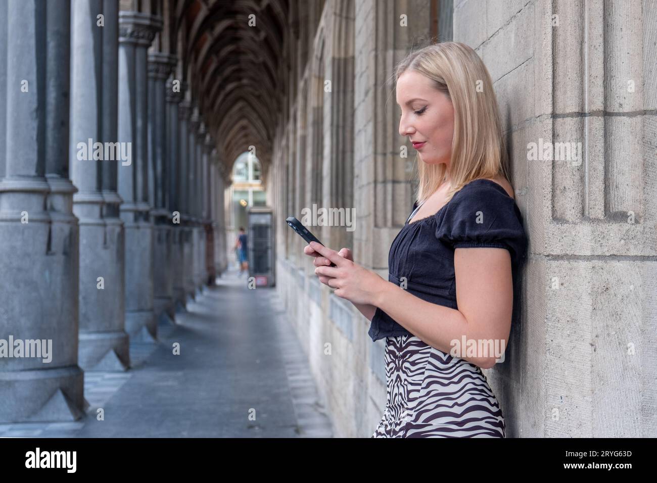 Heureuse blonde Millennial fille dans des vêtements à la mode riant sur le cadre urbain pendant la journée ensoleillée, positive joyeuse femme touriste dans un Banque D'Images