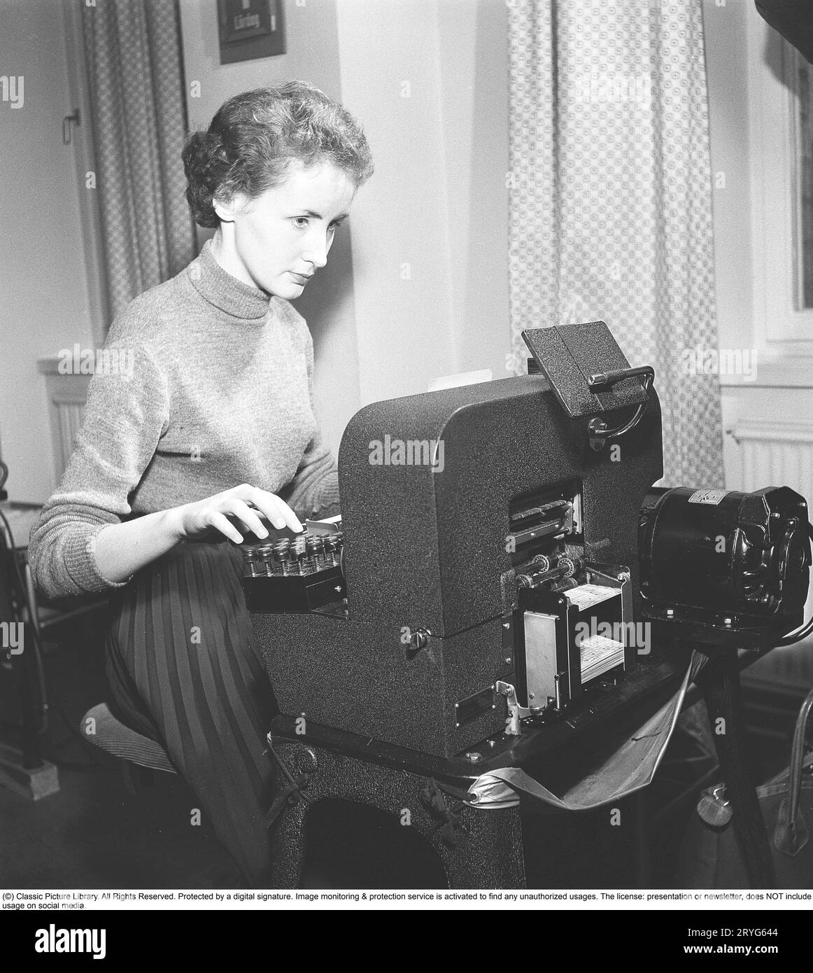 Dans les années 1950 Commis femme célibataire à la machine à cartes perforées entrant des informations dans des cartes perforées. Les cartes perforées étaient un support de stockage où les trous perforés dans la carte de papier étaient les informations d'entrée, et les trous et les informations étaient ensuite lus par une autre machine, un lecteur de cartes perforées, et les informations pouvaient ensuite être organisées ou imprimées. Suède 1954. Kristoffersson réf. BM85-12 Banque D'Images