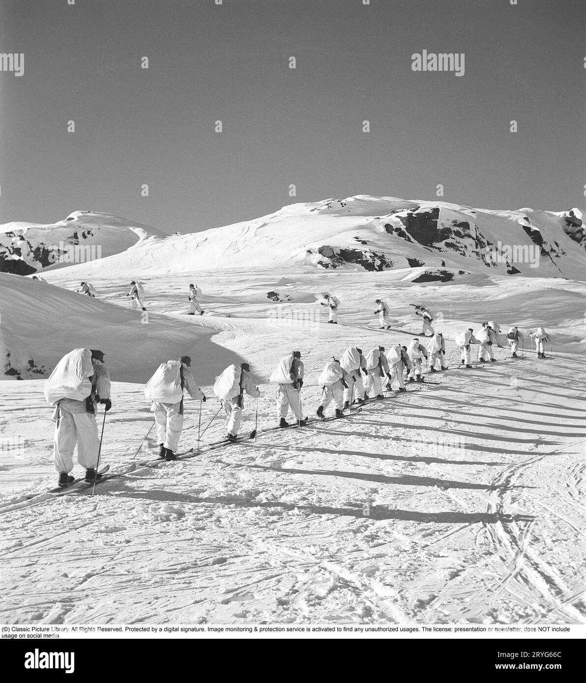 Soldats suédois pendant la Seconde Guerre mondiale. Des soldats armés vêtus de combinaisons blanches skient dans les montagnes suédoises. Suède 1943. Kristoffersson réf E5-3 Banque D'Images