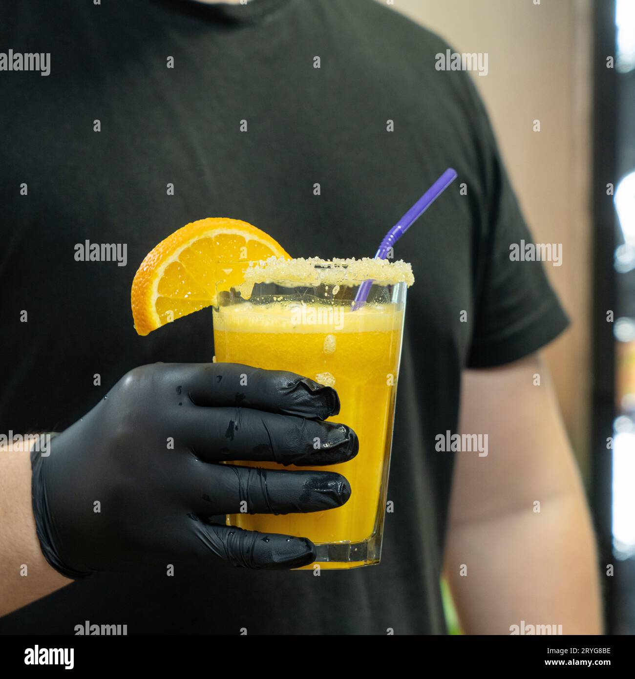 Un gros plan vertical du barman tenant un verre de boisson orange dans le complexe sportif Banque D'Images