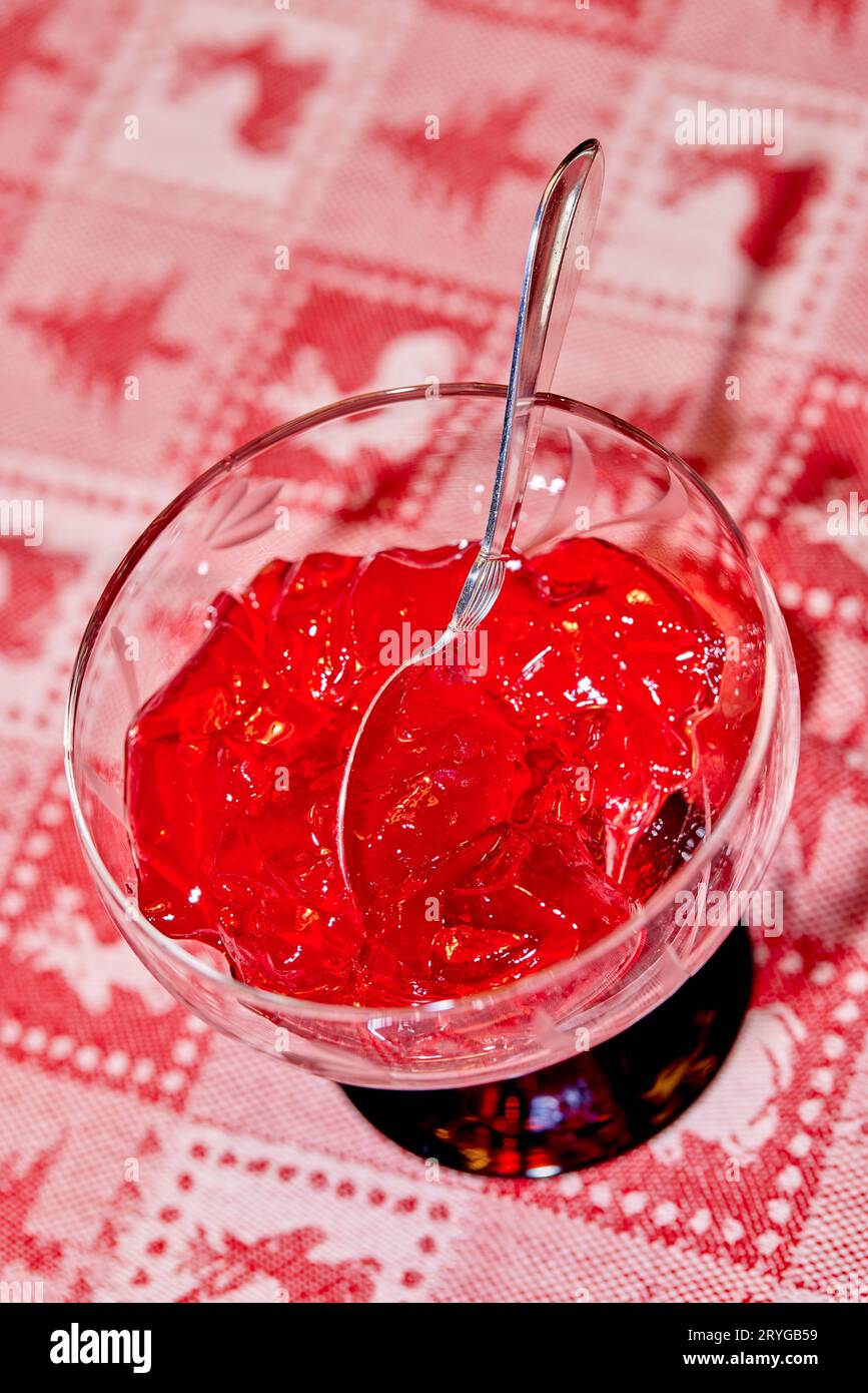Gelée rouge dans un bol en verre avec cuillère en argent, nappe de Noël Banque D'Images