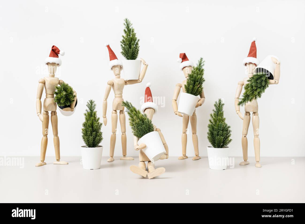 Groupe de mannequins en bois dans les chapeaux du Père Noël tenant des arbres de Noël. Arrière-plan de Noël Banque D'Images