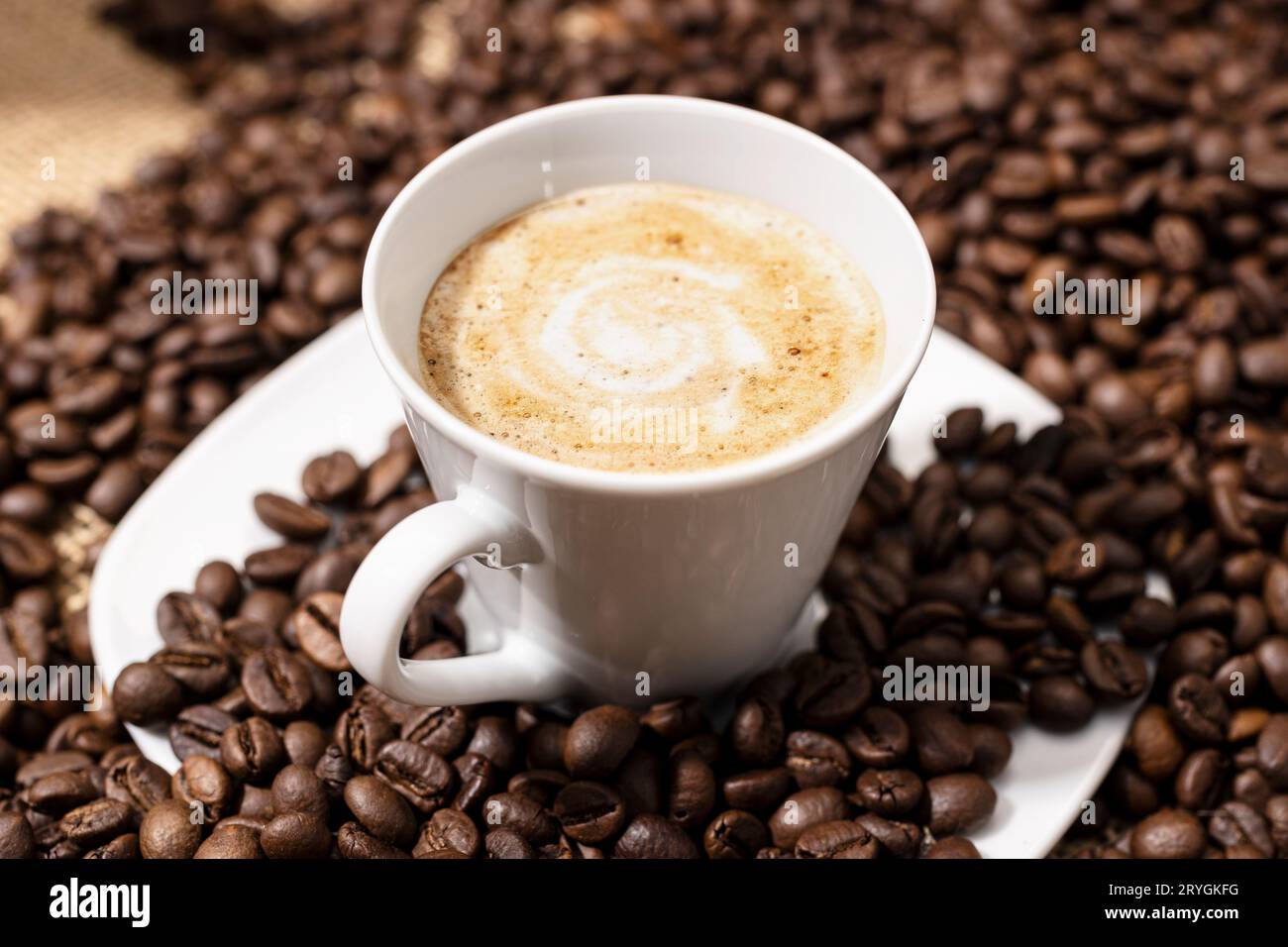 Café tasse tardive et grains torréfiés sur la table Banque D'Images