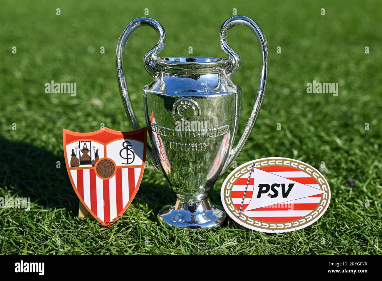 27 septembre 2023, Londres, Royaume-Uni. La coupe de la Ligue des champions de l'UEFA et les emblèmes des clubs de football Sevilla FC et PSV Eindhoven sur le green Banque D'Images