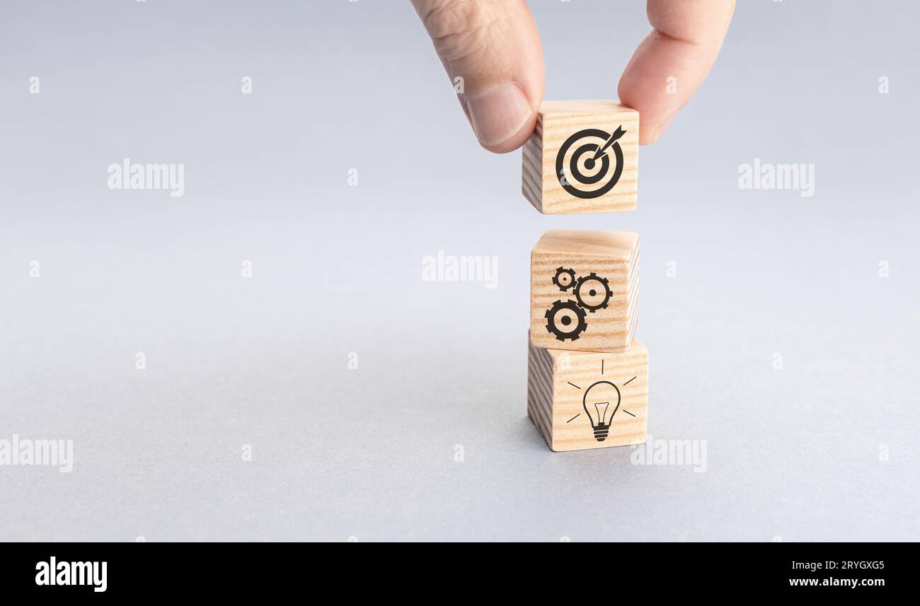 Stratégie commerciale et concept de plan d'action. Main mettant bloc de bois avec icône de cible sur le dessus des autres avec engrenage et ampoule ic Banque D'Images