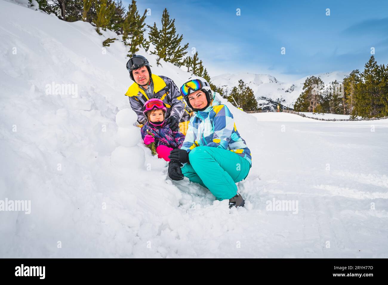 Famille construire un petit bonhomme de neige à côté de la piste de ski. Vacances d'hiver en Andorre Banque D'Images