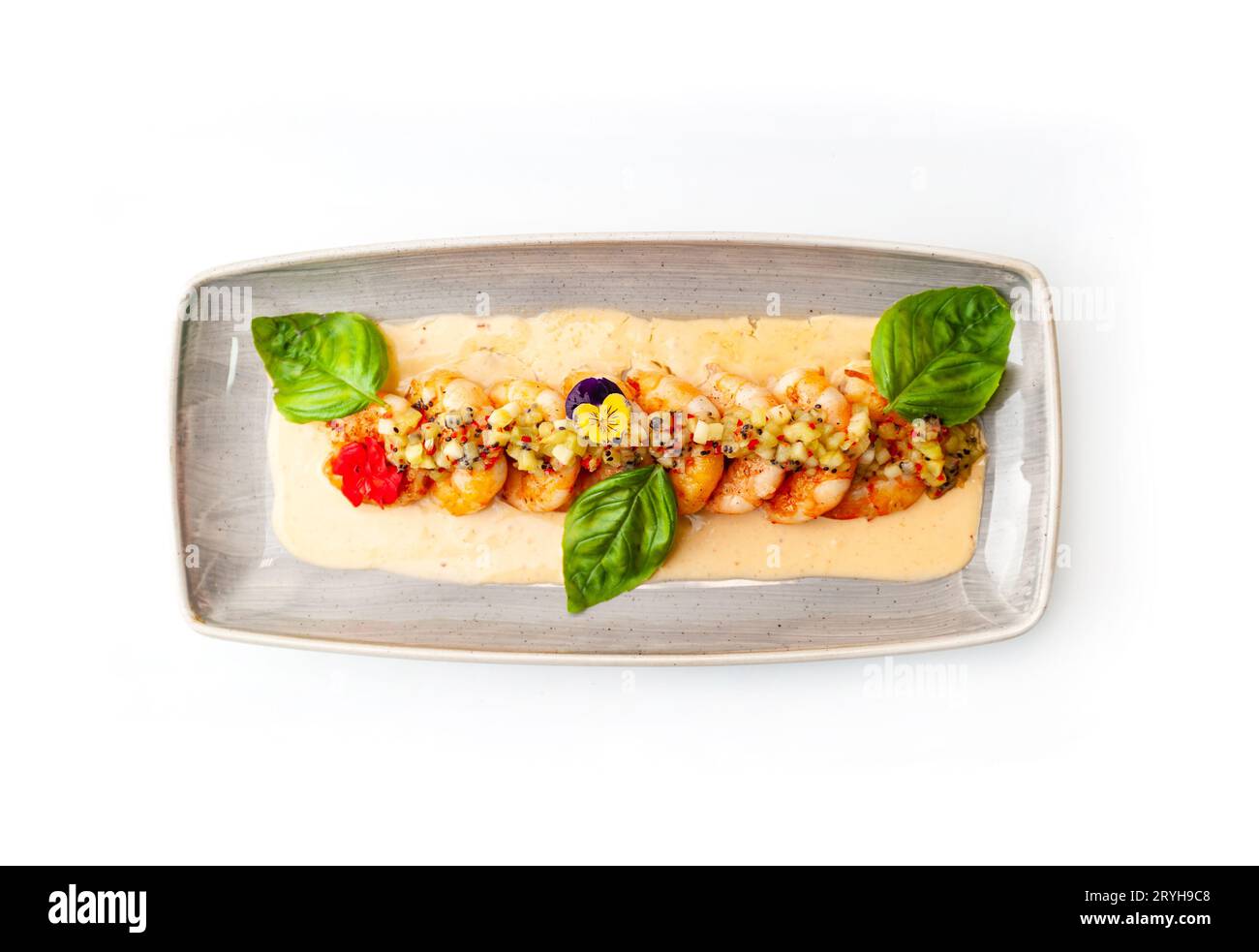 Crevettes frites en sauce crémeuse avec mangue et basilic sur une assiette grise isolée. Photo de haute qualité Banque D'Images