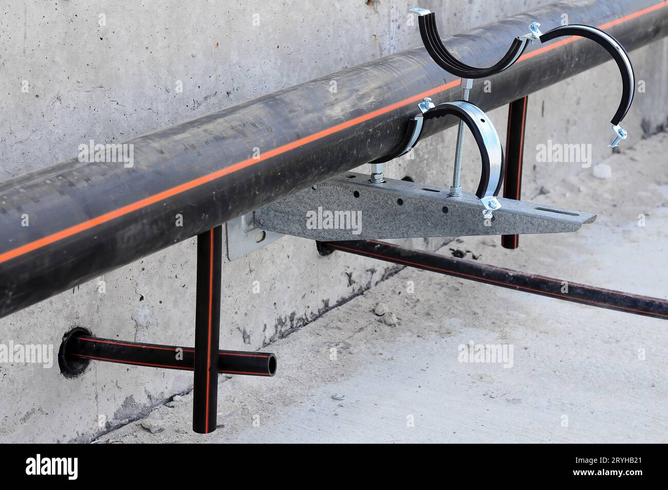 Tuyau en plastique noir en cours d'installation avant de souder les tuyaux de chauffage par le sol, sur un support métallique avec colliers Banque D'Images