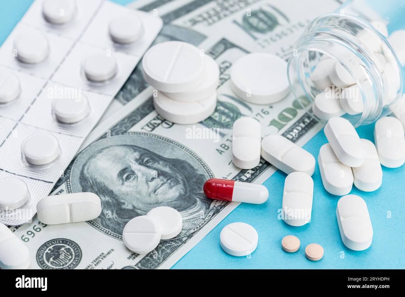 Coût élevé de la médecine concept. BILLETS ET pilules DE dollars AMÉRICAINS sur fond bleu Banque D'Images