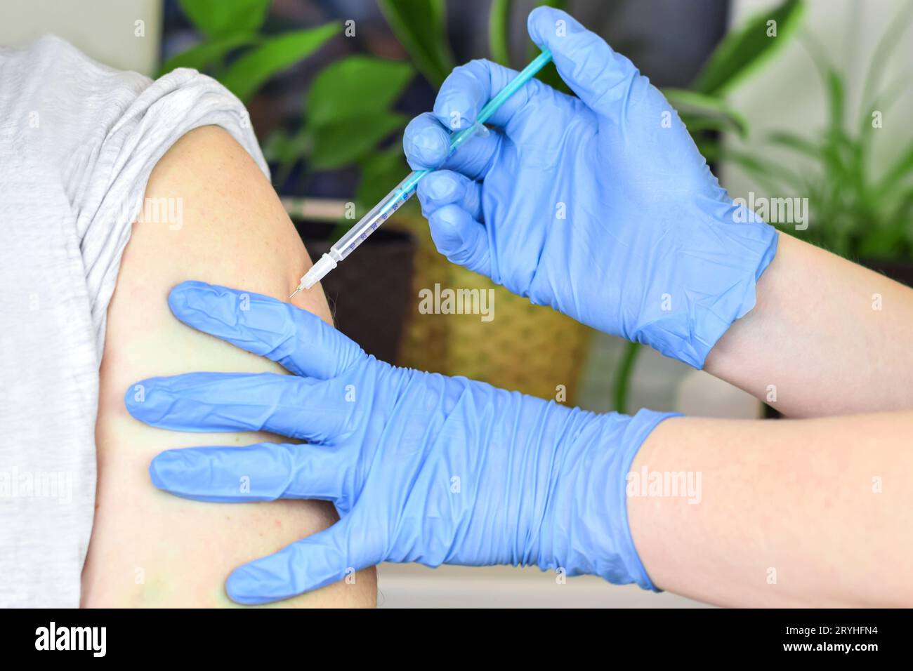 Gros plan des mains dans des gants bleus faisant une vaccination dans l'épaule du patient. Vaccination contre la grippe, injection sur le bras. Vaccin contre le coronavirus covid-19. COV Banque D'Images