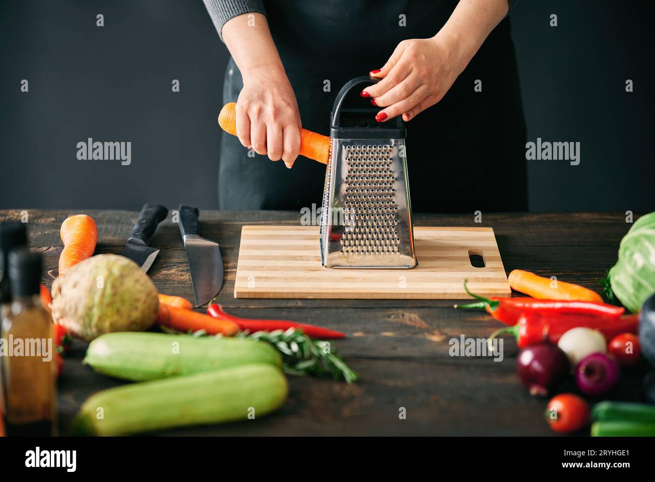 Femme cuisinant dans la cuisine à la maison, frotte les carottes sur une râpe Banque D'Images
