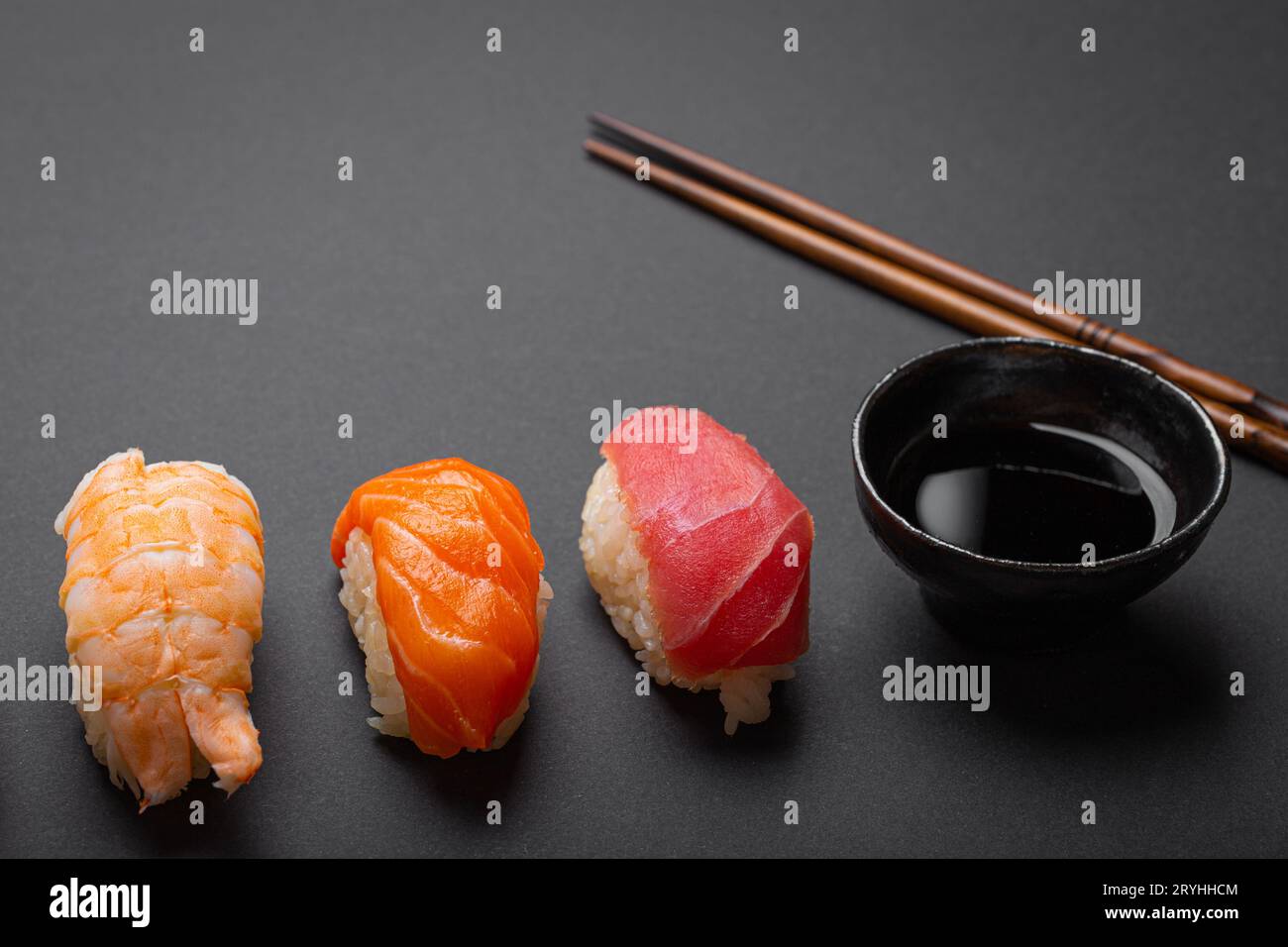 Sushi traditionnel japonais vue de dessus avec sauce soja et baguettes sur fond noir foncé minimal. Sushi au saumon, thon, shr Banque D'Images
