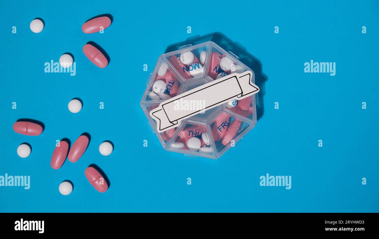 Gros plan de la boîte à pilules médicale avec des doses de comprimés pour prendre quotidiennement des médicaments avec des médicaments roses blancs et des capsules avec la note de papier COP Banque D'Images