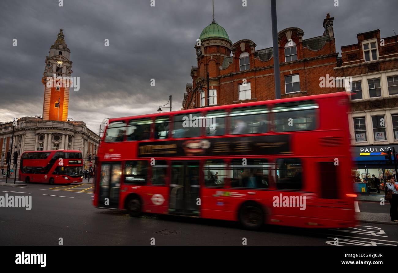 Brixton, Londres, Royaume-Uni : Red London bus sur Brixton Road (devenu Brixton Hill) avec la tour de l'horloge illuminée de Lambeth Town Hall en face. Banque D'Images