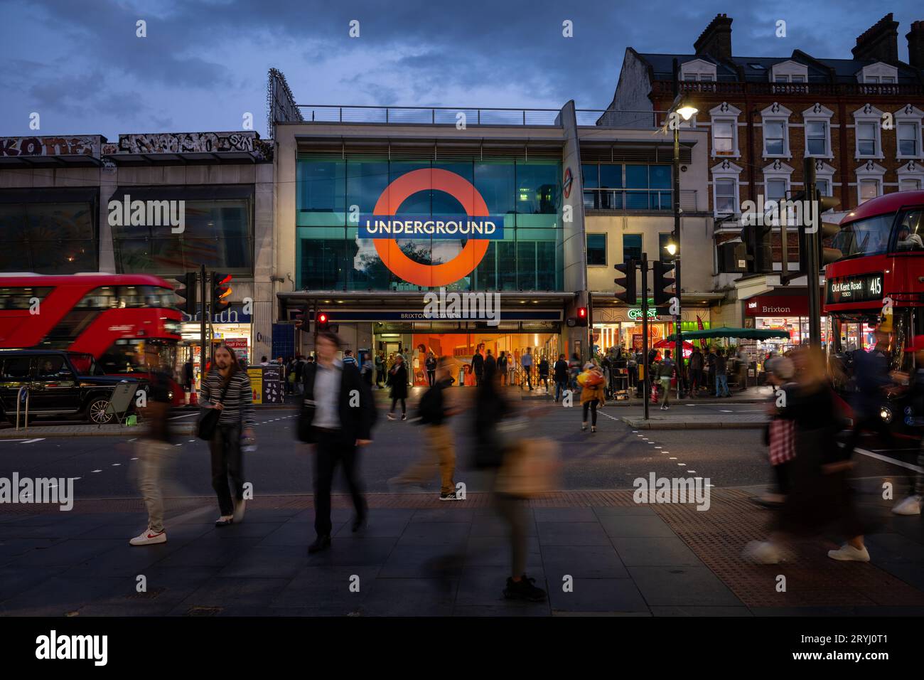 Brixton, Londres, Royaume-Uni : passage pour piétons sur Brixton Road en face de la station de métro Brixton. Vue en soirée avec les gens et les bus rouges de Londres. Banque D'Images