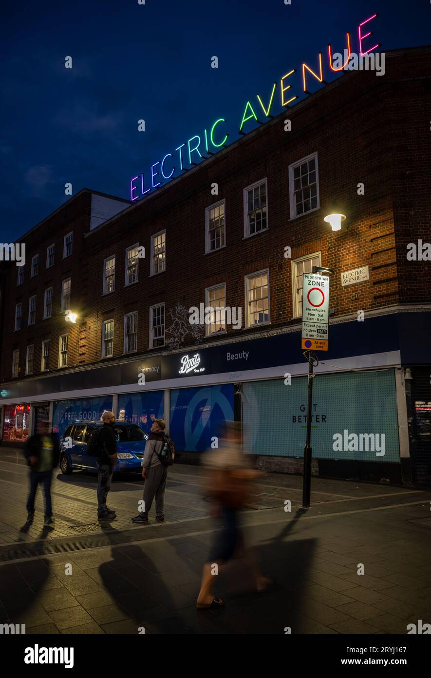 Brixton, Londres, Royaume-Uni : Electric Avenue à Brixton la nuit. Vu de Brixton Road avec le panneau coloré Electric Avenue au néon. Banque D'Images