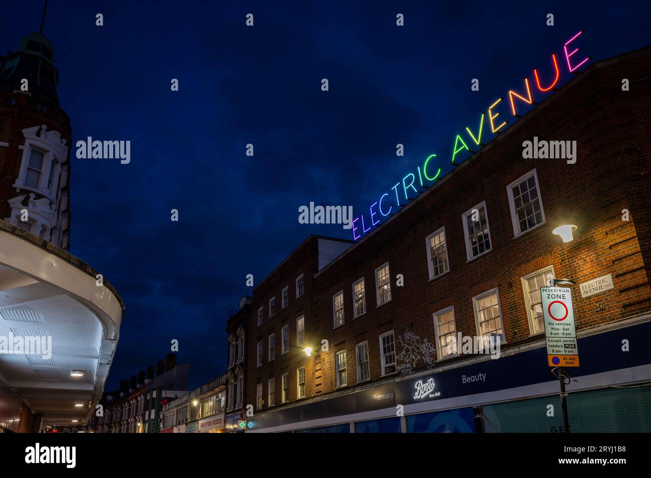 Brixton, Londres, Royaume-Uni : Electric Avenue à Brixton la nuit. Vu de Brixton Road avec le panneau coloré Electric Avenue au néon. Banque D'Images