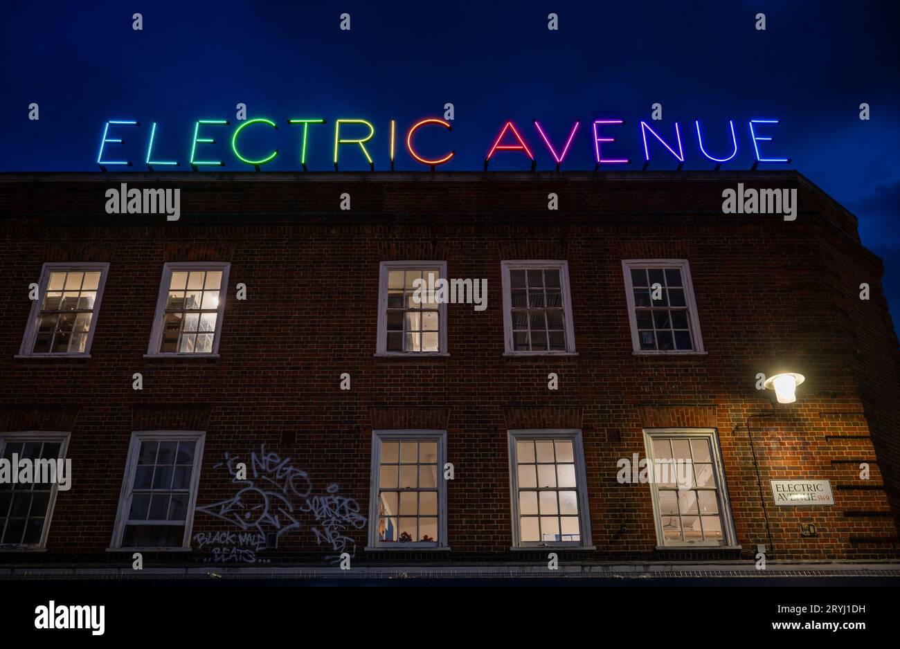 Brixton, Londres, Royaume-Uni : Electric Avenue à Brixton la nuit. Bâtiment avec l'enseigne au néon colorée Electric Avenue ci-dessus. Banque D'Images