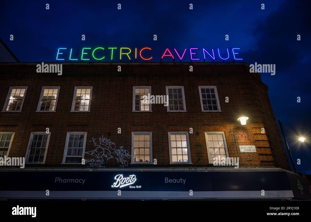 Brixton, Londres, Royaume-Uni : Electric Avenue à Brixton la nuit. Bâtiment avec l'enseigne au néon colorée Electric Avenue ci-dessus. Banque D'Images