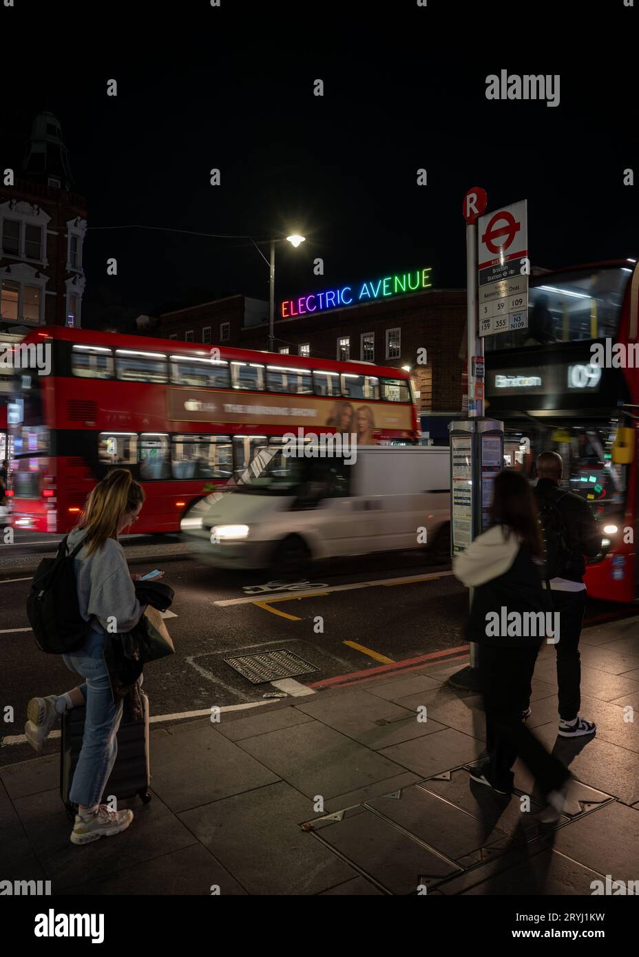 Brixton, Londres, Royaume-Uni : les gens attendent à un arrêt de bus sur Brixton Road en face de Electric Avenue. Banque D'Images