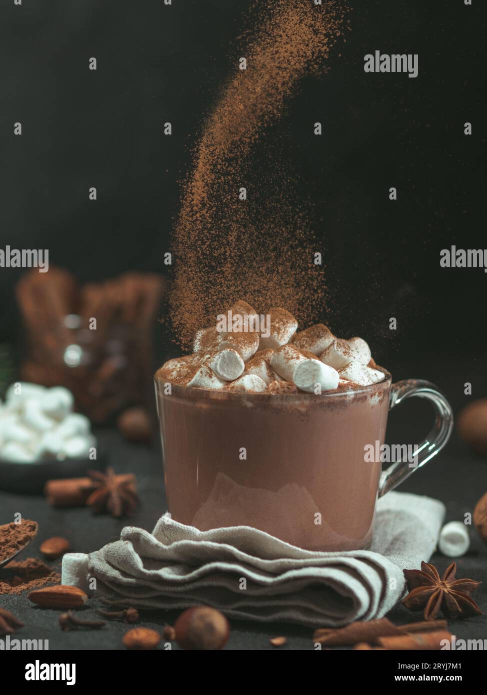 Poudre de cannelle survolant une tasse en verre avec du chocolat chaud Banque D'Images