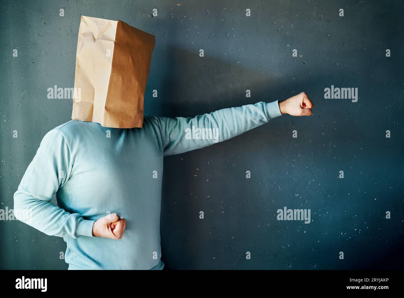 Vue latérale de l'homme avec un sac en papier sur la tête avec les poings serrés en position de combat, pratiquant le poinçonnage de karaté Banque D'Images