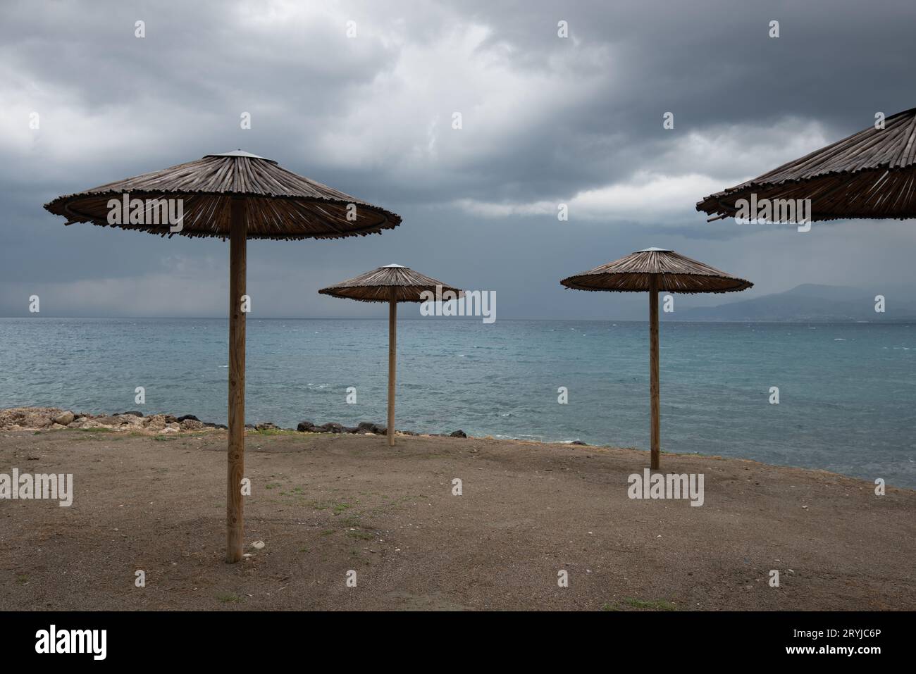 Parasols de plage vides sur une côte rocheuse en hiver. Vacances d'été Paphos Chypre Banque D'Images