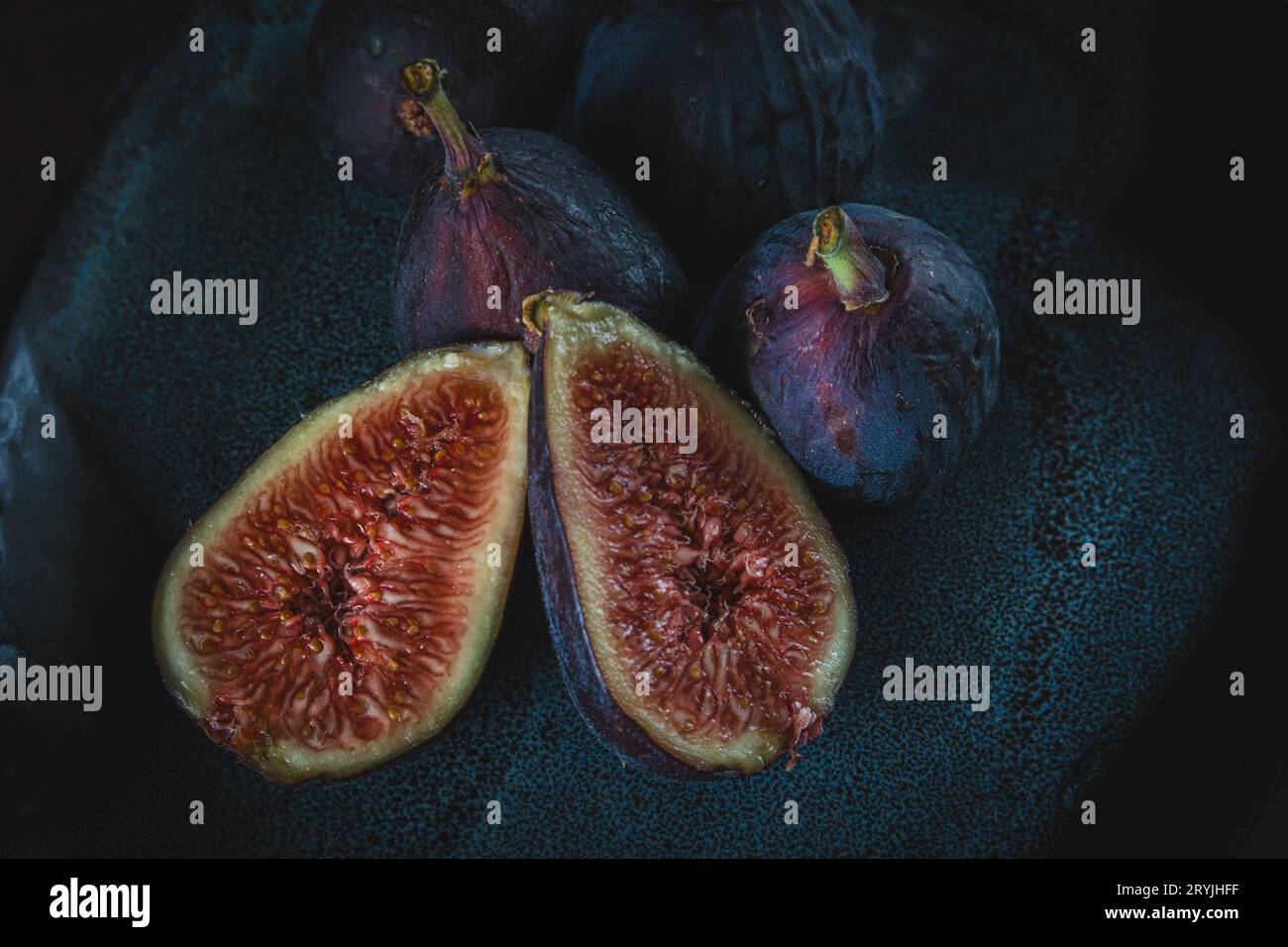 gros plan photo de figues aux fruits frais ; coupées et prêtes à servir, trois figues entières sur un fond sombre. Banque D'Images