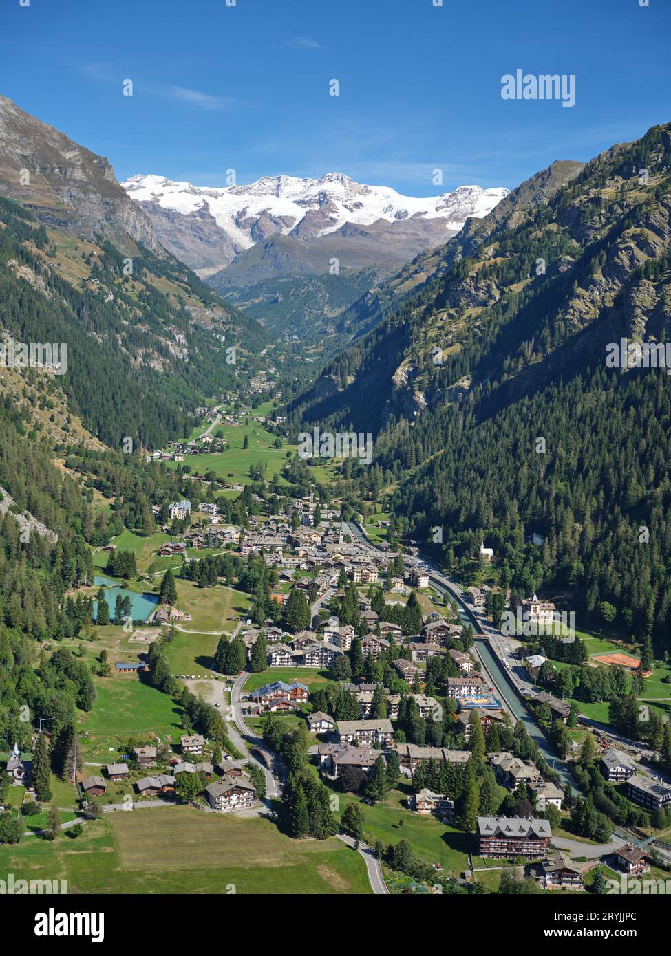 VUE AÉRIENNE. Village de Gressoney-Saint-Jean avec le mont Lyskamm (4533 mètres) au loin. Vallée d'Aoste, Italie. Banque D'Images