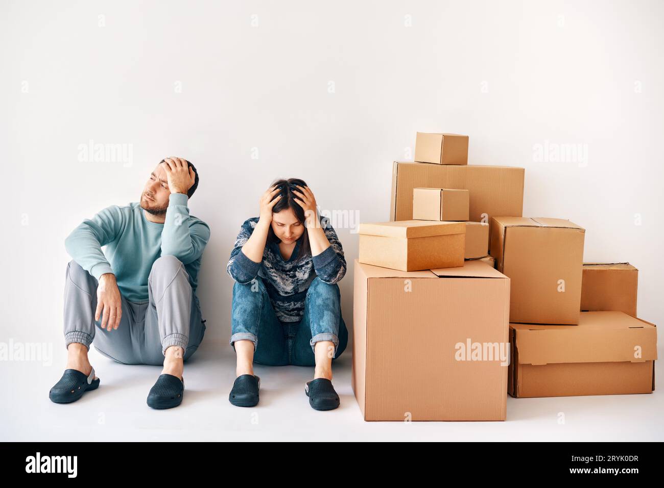 Jeune couple s'est endormi après une journée de déménagement assis sur le sol entouré de boîtes en carton Banque D'Images