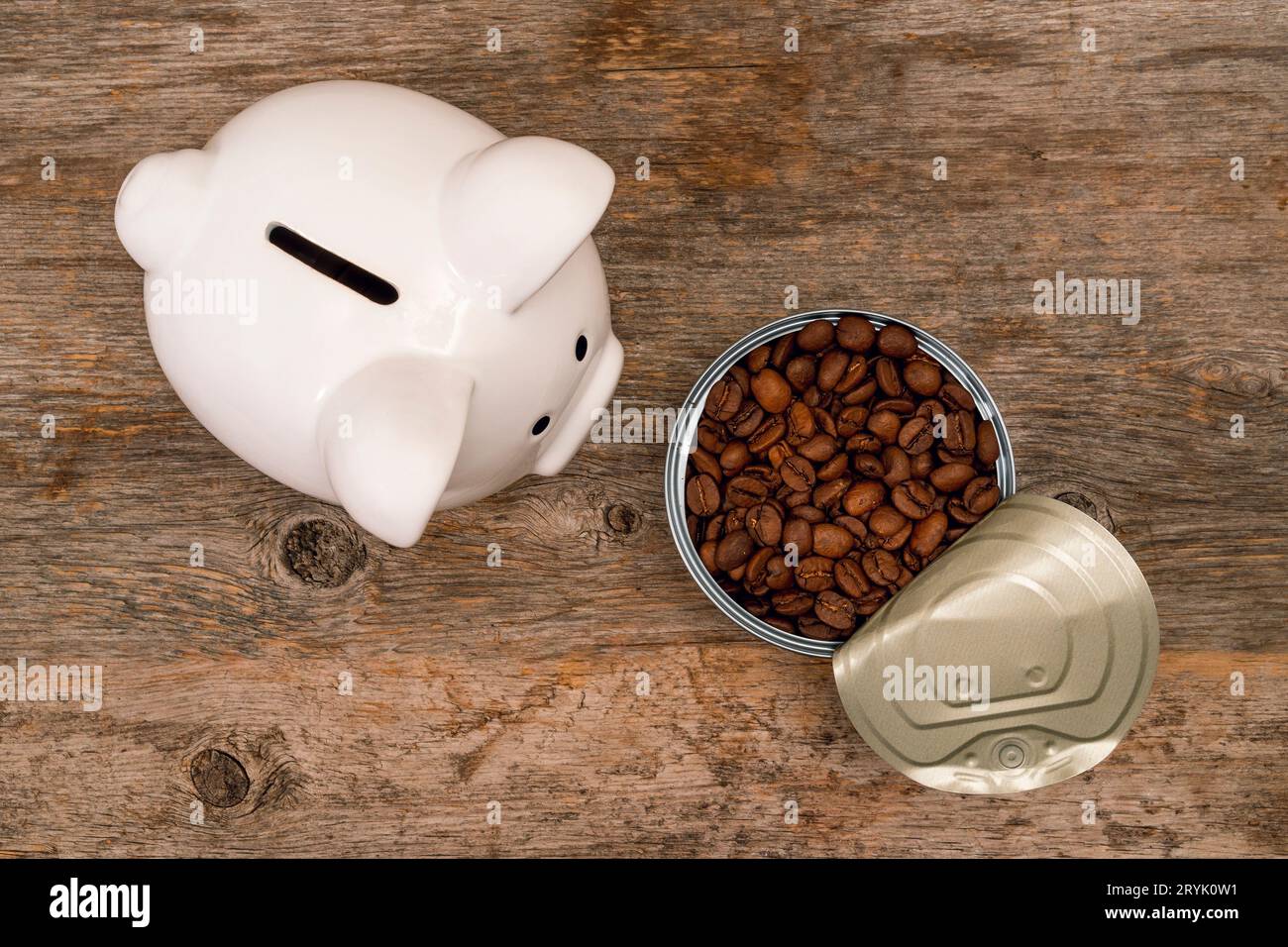 Tirelire à côté d'une boîte de conserve ouverte pleine de grains de café torréfiés Banque D'Images