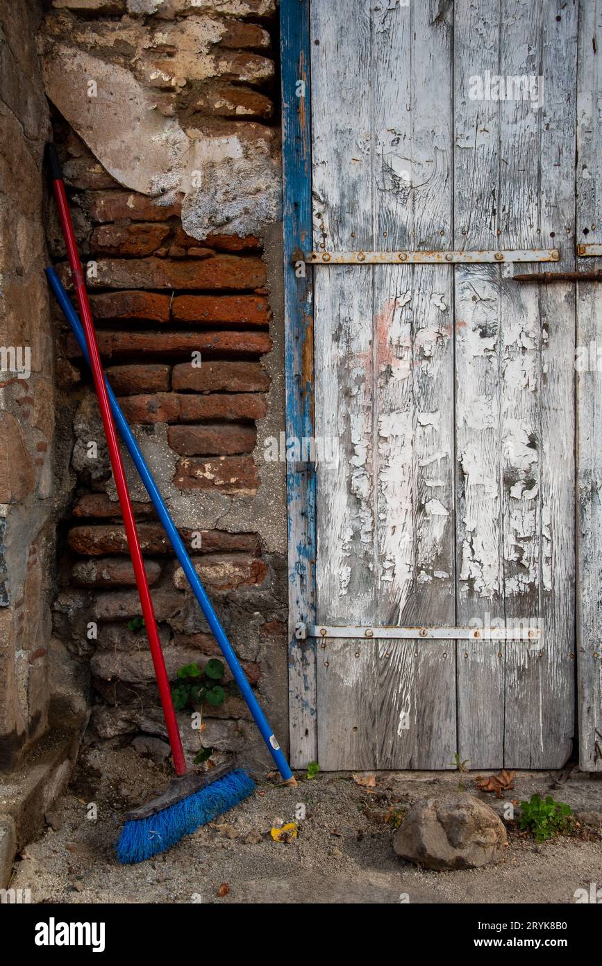 Porte en bois fermée et balai rouge à l'extérieur d'une maison traditionnelle en briques Banque D'Images