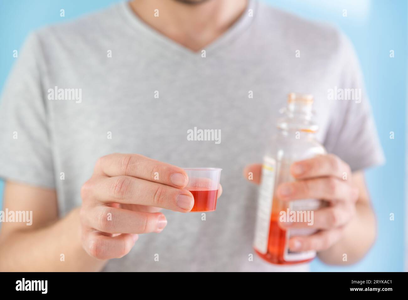 Homme tenant la portion de sirop de médicament liquide pour le traitement du rhume et de la grippe dans la tasse à mesurer. Homme buvant un médicament liquide à partir d'une bouteille de médicaments. Prendre des médicaments Banque D'Images