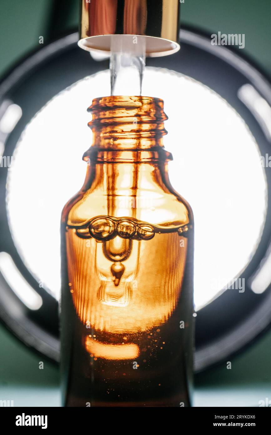 Pipeter avec de l'huile cosmétique dans une bouteille brune avec des bulles Banque D'Images