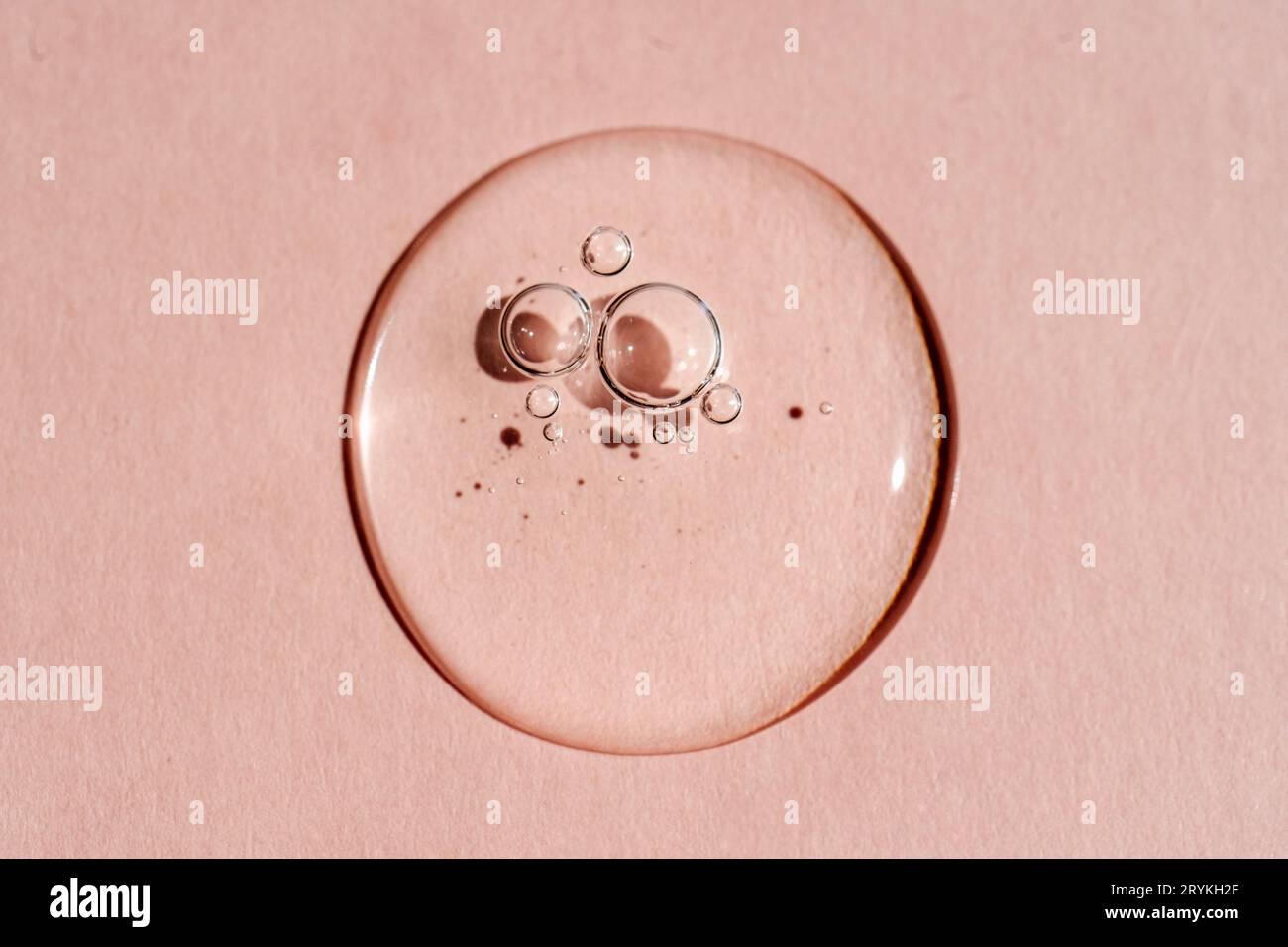 Une goutte de gel cosmétique transparent sur fond rose. Banque D'Images