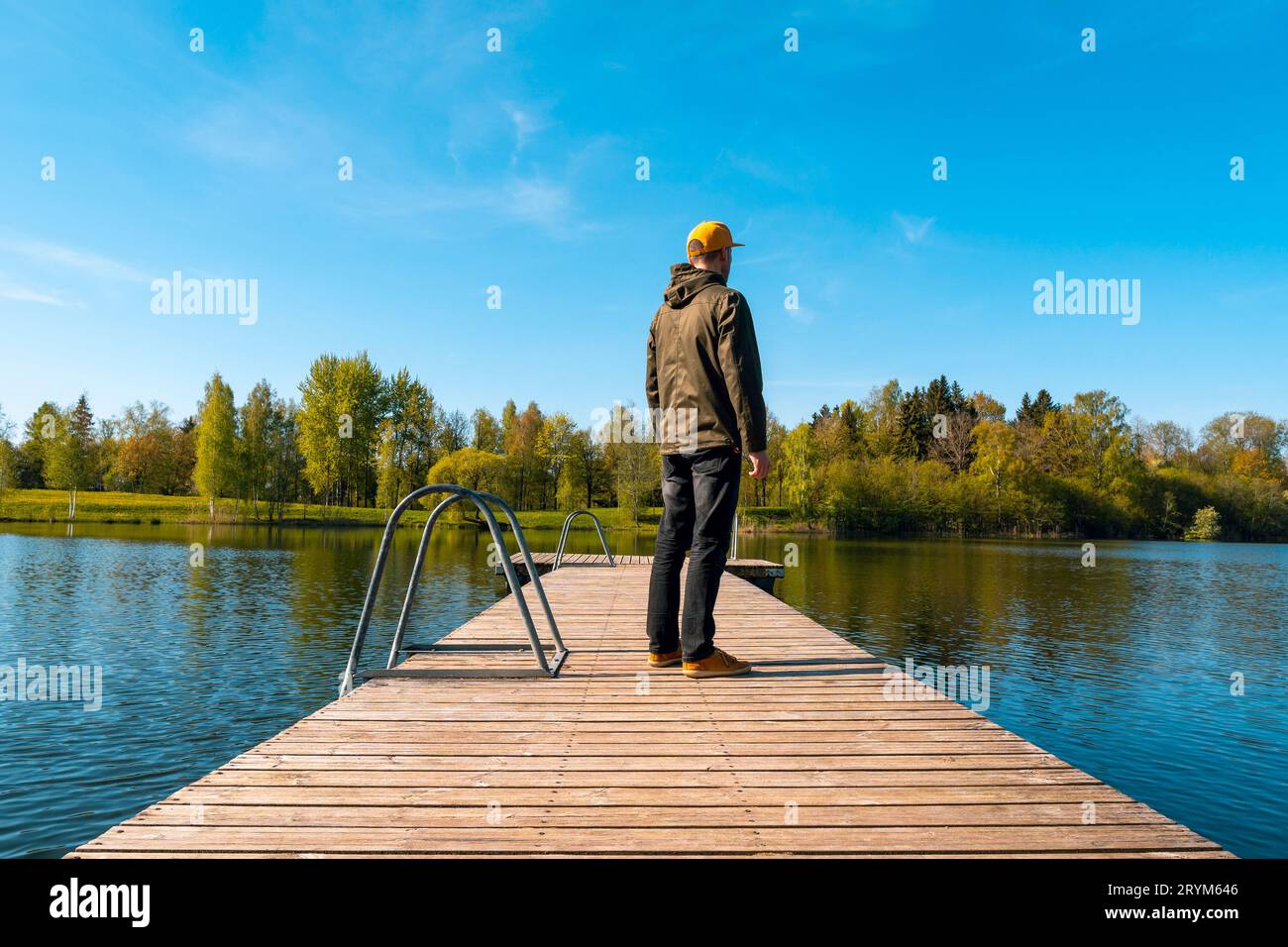 Jeune homme debout seul sur un pont en bois et regardant le lac Banque D'Images