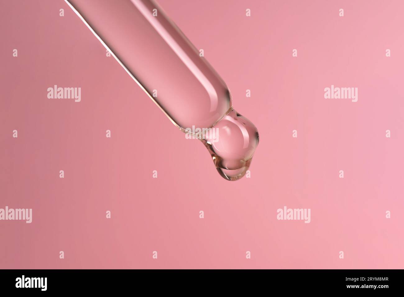 Compte-gouttes avec sérum ou huile cosmétique sur fond rose. Banque D'Images